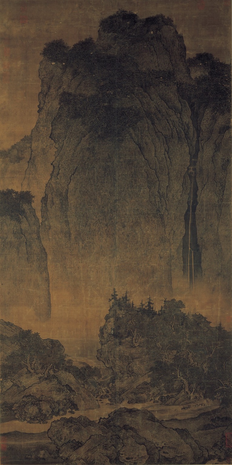 A hanging scroll of a great mountain rising over mist and a waterfall, with a small train of travellers and mules on the path below